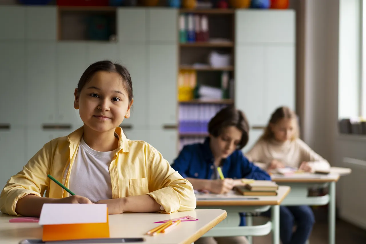 Niños trabajando en clase de primaria con materiales escolares sobre la mesa