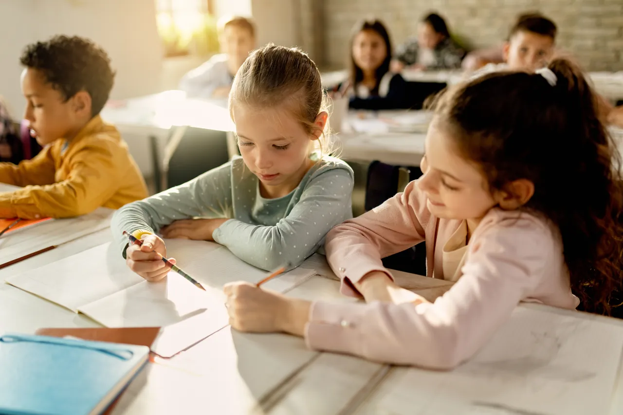Niño haciendo los deberes sobre una mesa con cuadernos y lápices