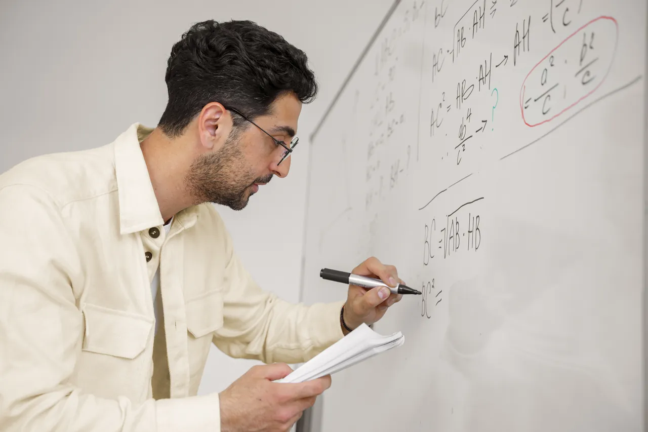 Profesor particular de matemáticas de bachillerato resolviendo un problema en la pizarra